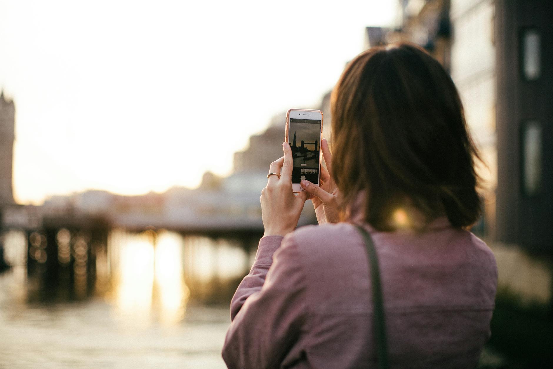 woman wearing maroon long sleeved shirt holding smartphone